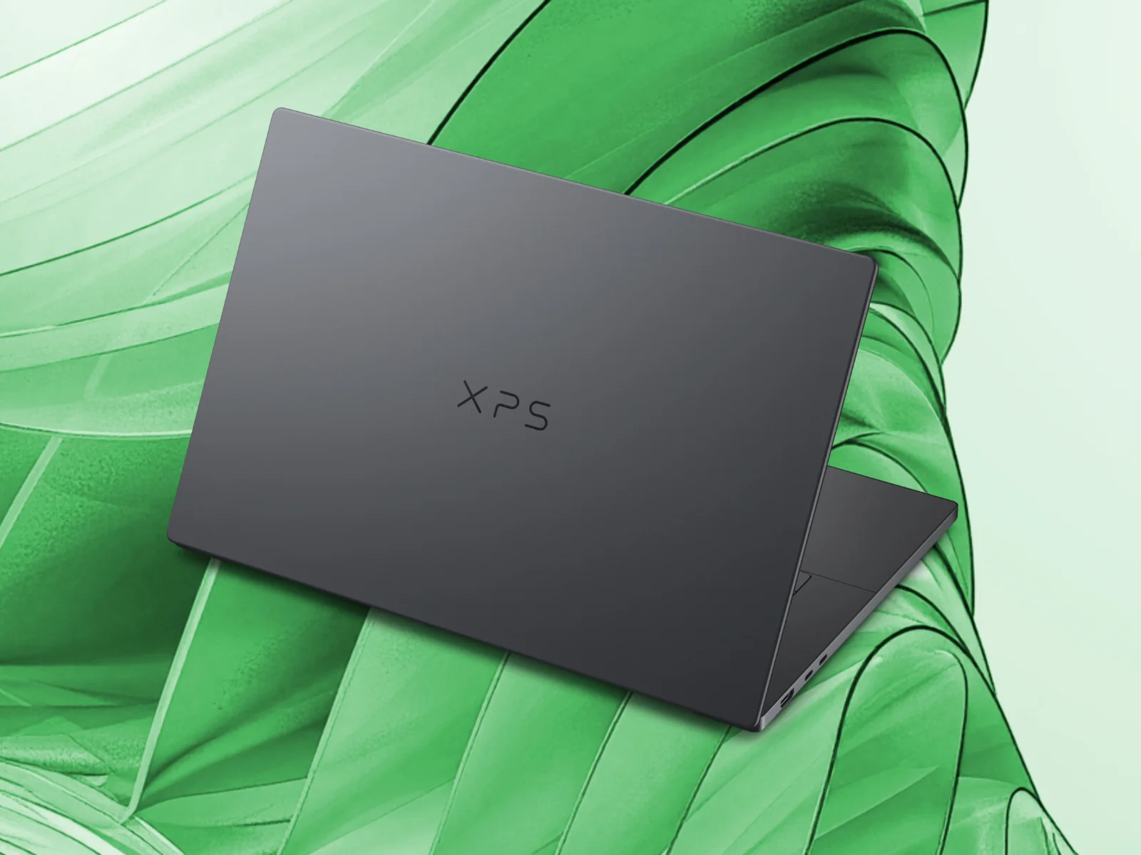 Серый ноутбук Dell XPS 16 Creator Edition с приоткрытой крышкой на зелёном фоне