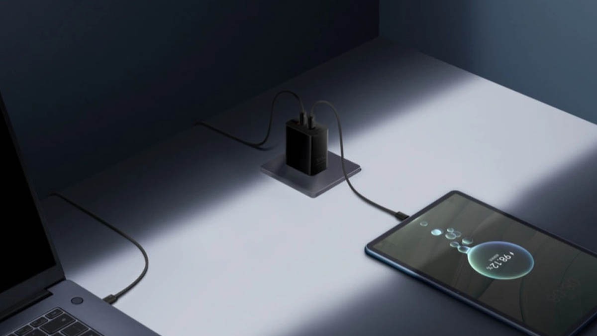 Чёрный адаптер Huawei 66W Power Edition рядом с планшетом и ноутбуком