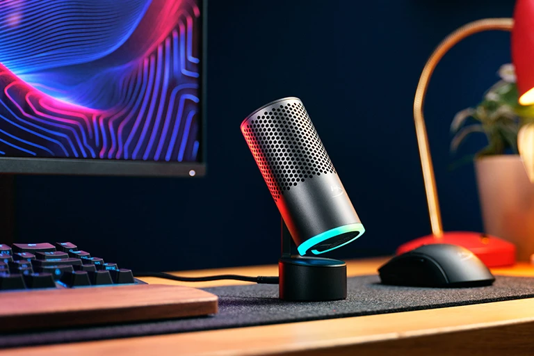 Микрофон HyperX SoloCast 2 Pro с цветным световым кольцом на столе рядом с клавиатурой, монитором и мышью