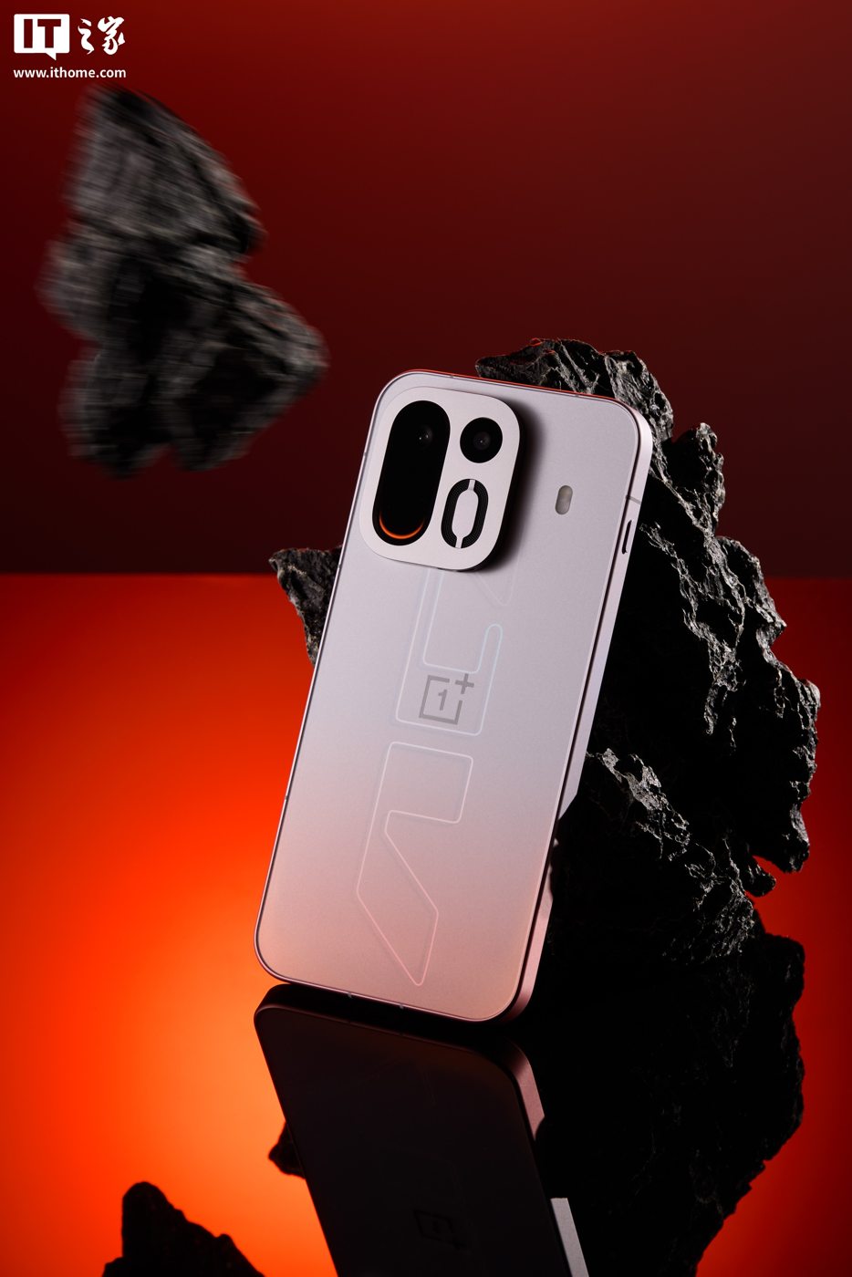 Светлый смартфон OnePlus Ace 7 задней панелью к зрителю на чёрном камне и красном фоне
